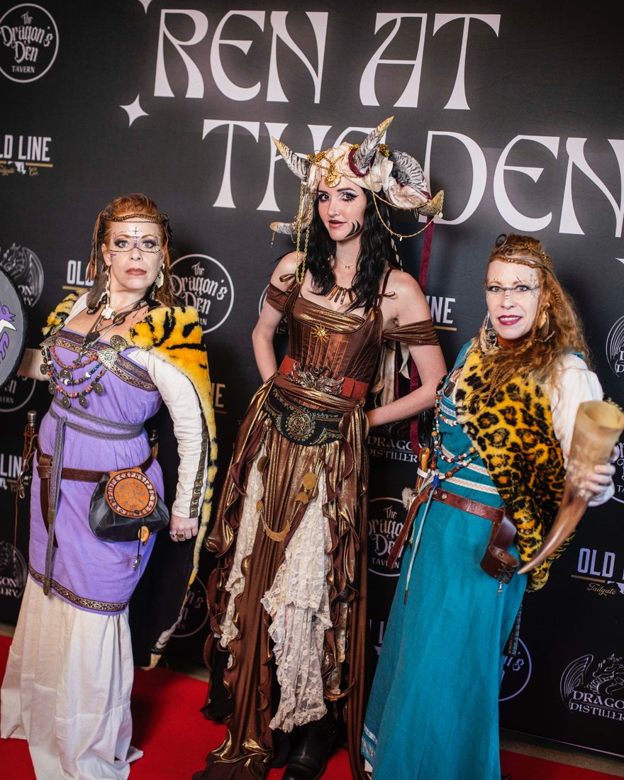 Three guests in warrior garb — horned headdress, furs and drinking horn — at the photo wall